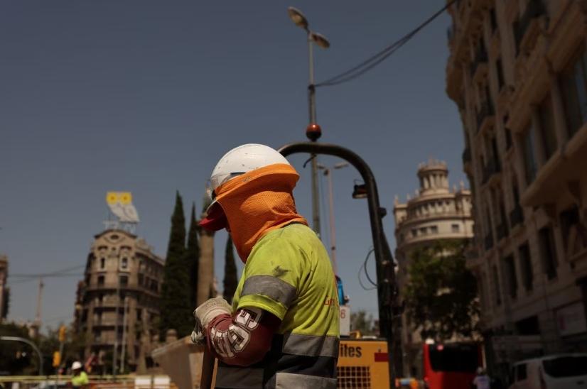 Un trabajador está cubierto mientras trabaja en una calle de Barcelona, ​​España.